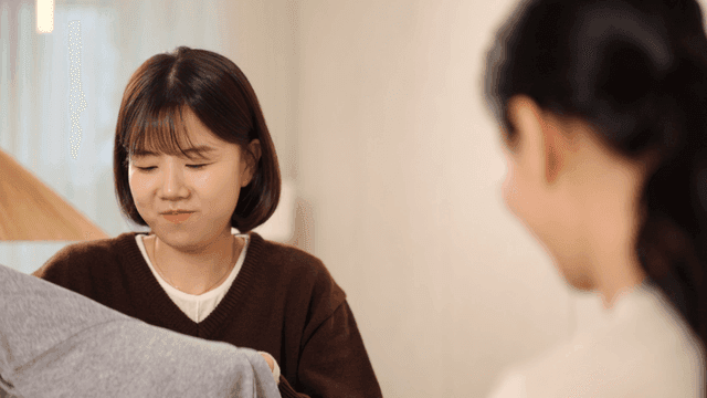 Mother and daughter folding clothes together at home