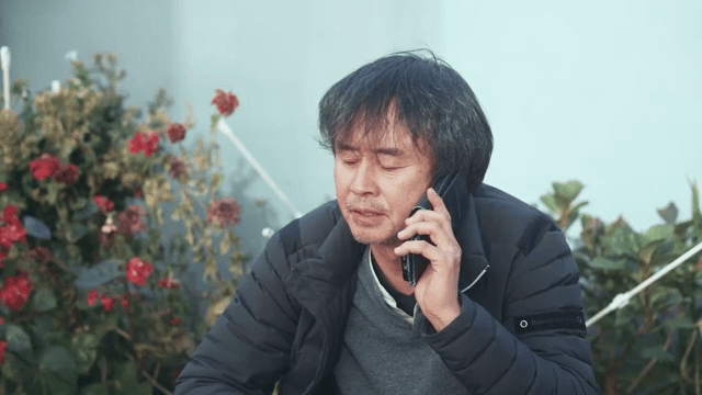 Man talking on the phone near red flowers
