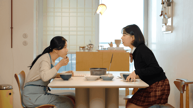 High school daughter eating breakfast with her mother before going to school.