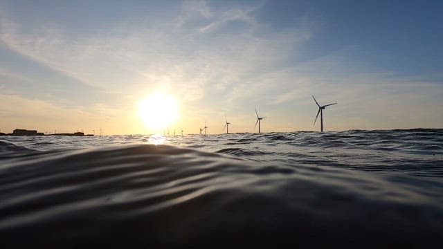 Sunset on the ocean with wind turbines spinning