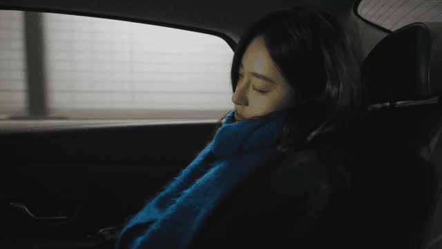 Side view of a woman sleeping in a dark taxi