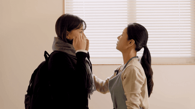 Mother tying scarf to her daughter as she goes to school