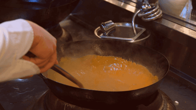 Chef stirring curry in wok in kitchen
