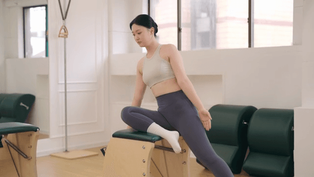 Woman practicing pilates on equipment
