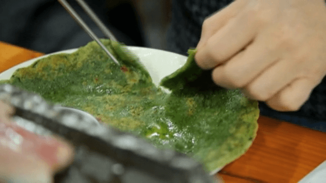 젓가락과 손을 이용해 자르는 쑥빈대떡