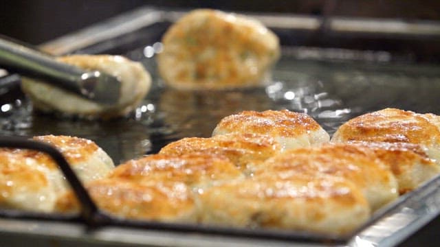 Crispy fried dumplings being cooked on a griddle