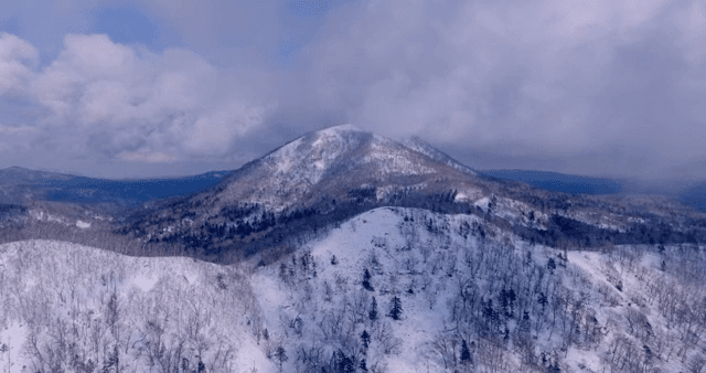 구름 낀 하늘 아래 눈 덮인 산