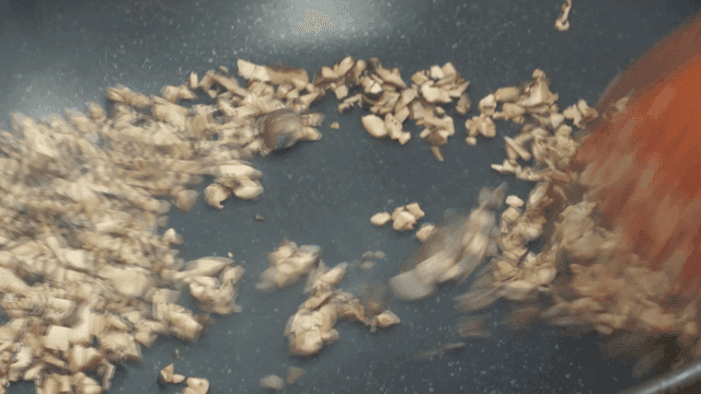 Chopped mushrooms being sautéed in a pan