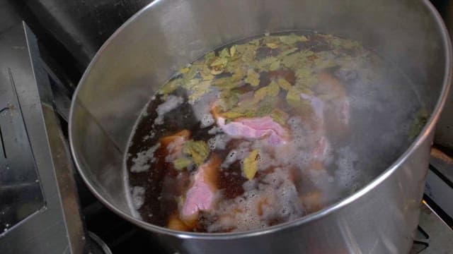 Large pot of meat and spices boiling on stove