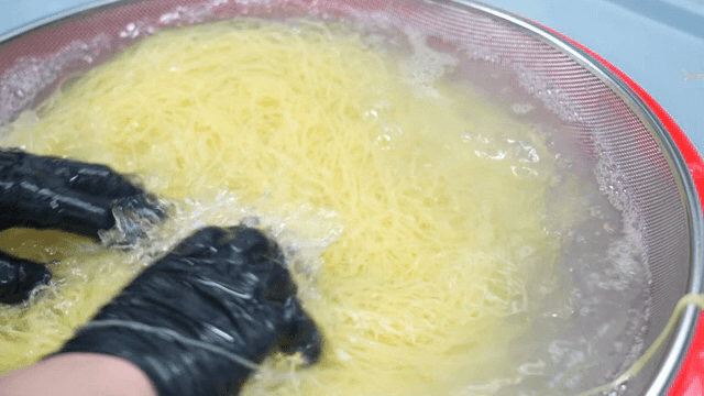 체에 삶은 면을 헹구는 모습