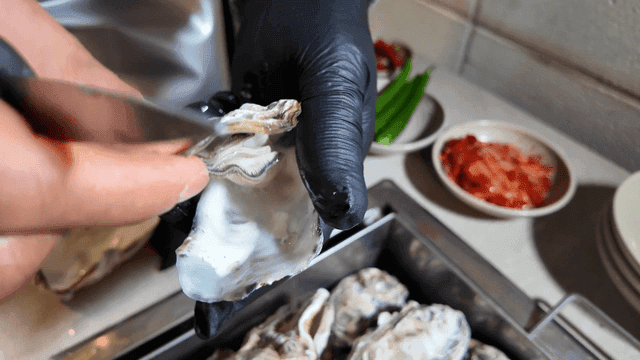 Opening fresh steamed oyster