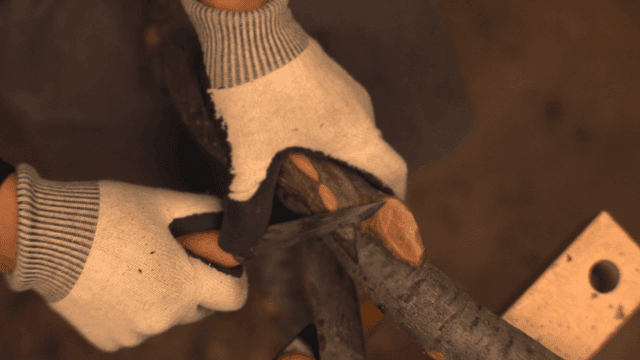 실내에서 나무 가지를 깎는 사람