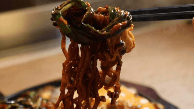 Green onion kimchi and jajang ramen picked up with chopsticks