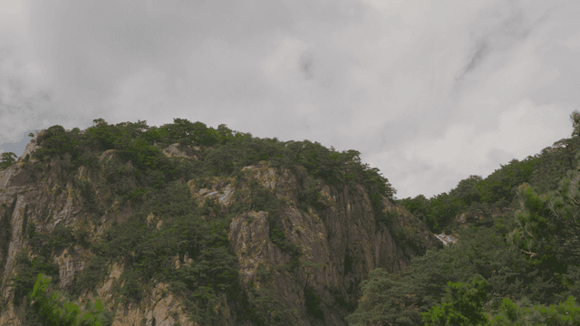 구름 낀 하늘 아래 푸른 바위 산