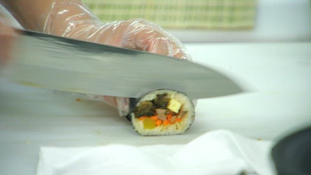 Slicing kimbap made of mustard leaves with a sharp knife