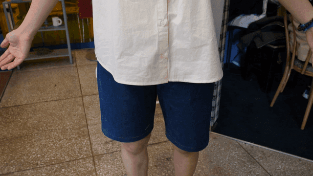 Person showing themselves wearing white shirt and denim shorts