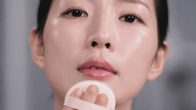 Woman applying makeup with cushion puff