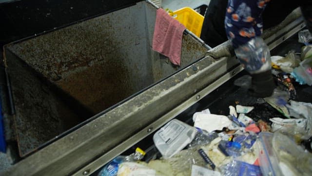 Workers sorting and discarding recyclables in a plant