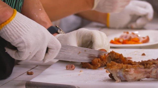 Cutting cooked pig trotters with a cleaver on a cutting board