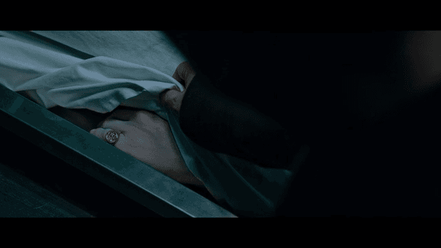 A hand uncovering a body in a morgue