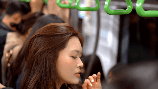 Tired woman standing and holding onto handrail in crowded subway
