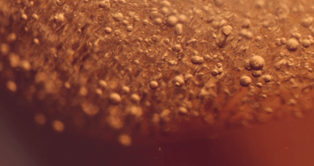 Movement of water droplets in orange liquid