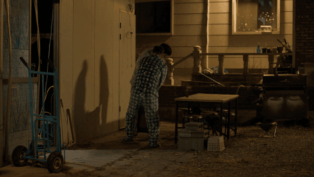 Two men in pajamas moving a heater outside