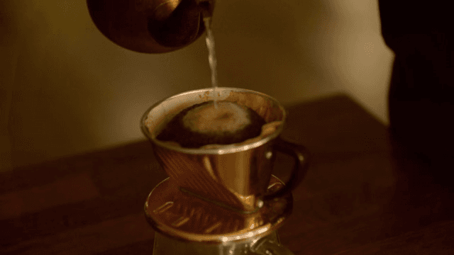 금빛 주전자로 핸드드립 커피를 내리는 모습