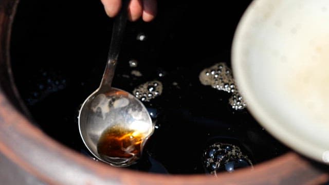 Scooping clear soy sauce from a crock with a ladle