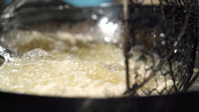 주방에서 웍의 뜨거운 기름에 고기를 튀기기