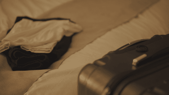 침대 위에 놓인 여행 가방과 옆의 옷