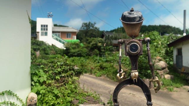 Robot standing on a country road with lush greenery