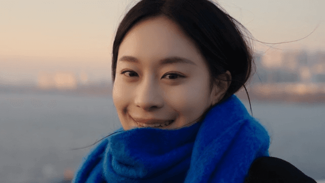 Woman smiling and looking straight ahead at the evening river