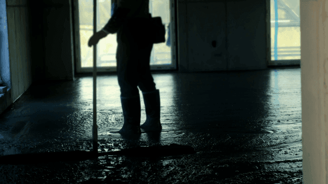 실내에서 콘크리트 바닥을 고르는 작업자