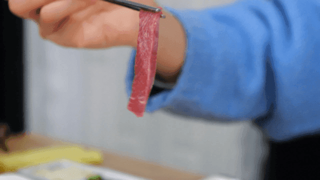 Fresh red yellowtail sashimi picked up with chopsticks