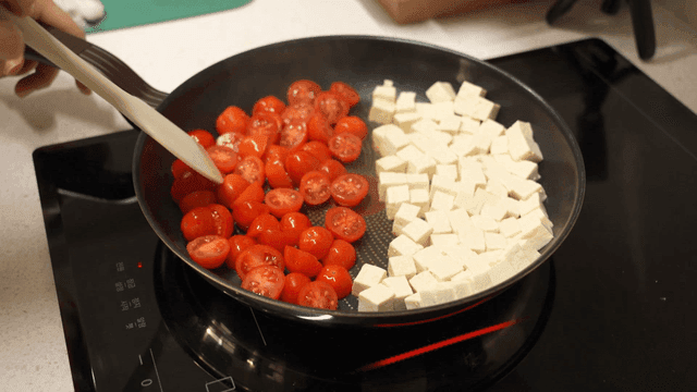 Cooking cherry tomatoes and tofu in a pan