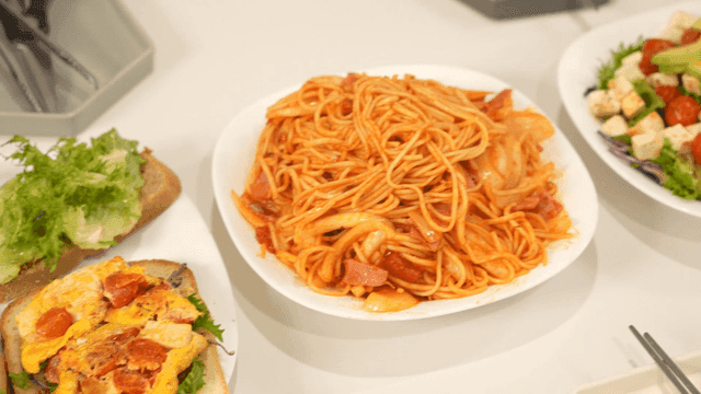 Table with sandwiches, salad, and tomato spaghetti.