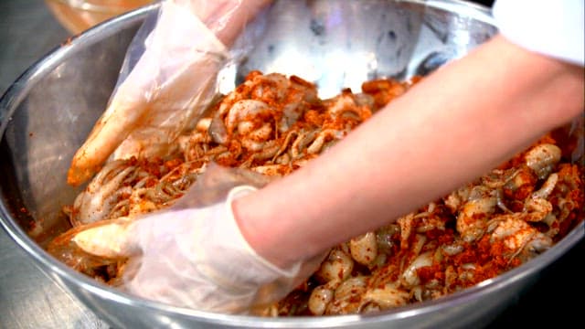 Mixing seasoned webfoot octopus in a large basin