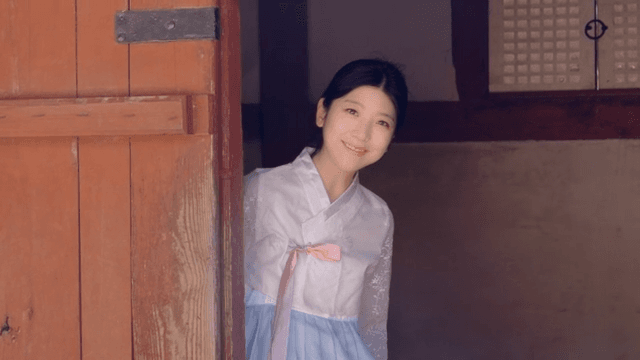 Woman in hanbok smiling at the door
