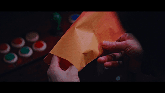Hand pulling unknown card from envelope under dim light