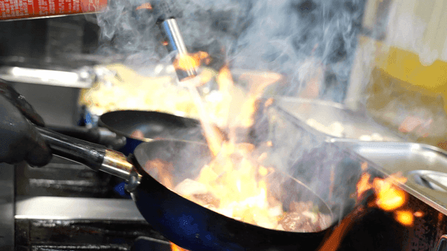 Frying pan with flames shooting up while cooking