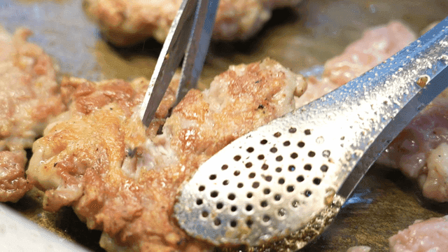 Chicken being cut with scissors on hot grill