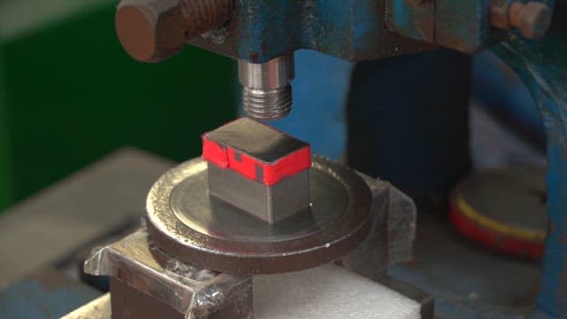 Metal block being pressed in a machine