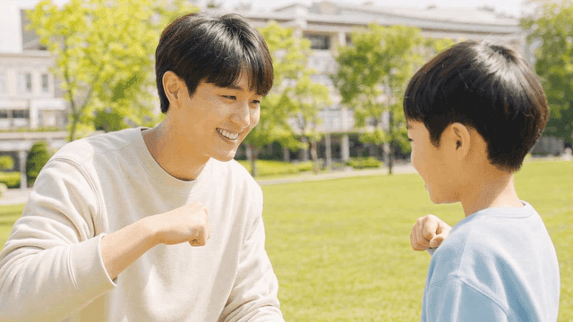 Man and child exchanging fist bumps in park