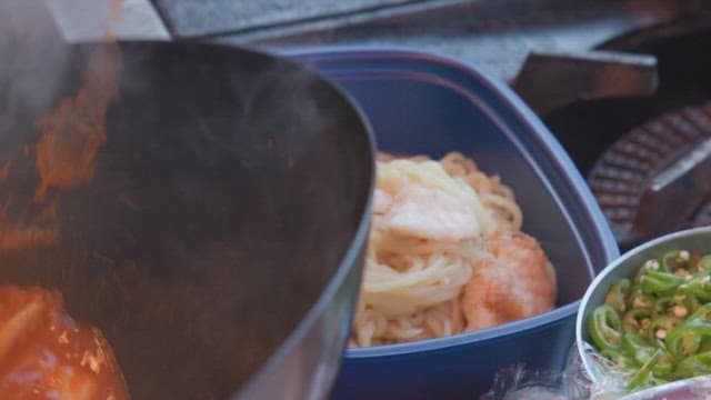 Preparing freshly cooked spicy seafood Jjamppong in a plastic container