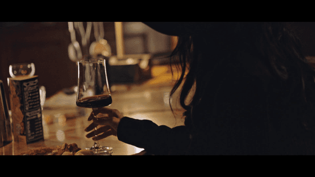 Woman in hat enjoying wine in cozy bar