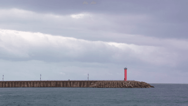 흐린 날의 바다 위 빨간 등대