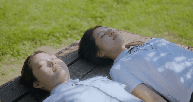 나무 벤치에서 누워서 휴식 중인 두 소녀