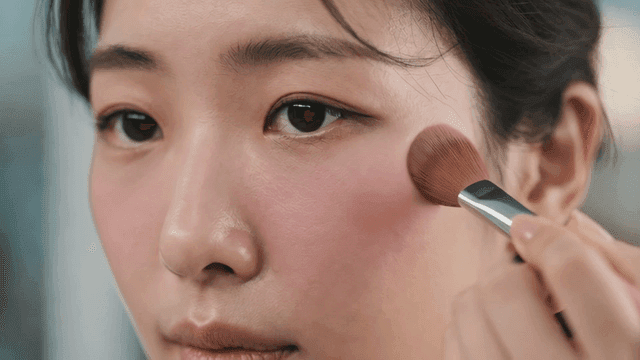 Woman applying blush to her cheeks