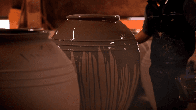 Applying glaze to a large pottery jar